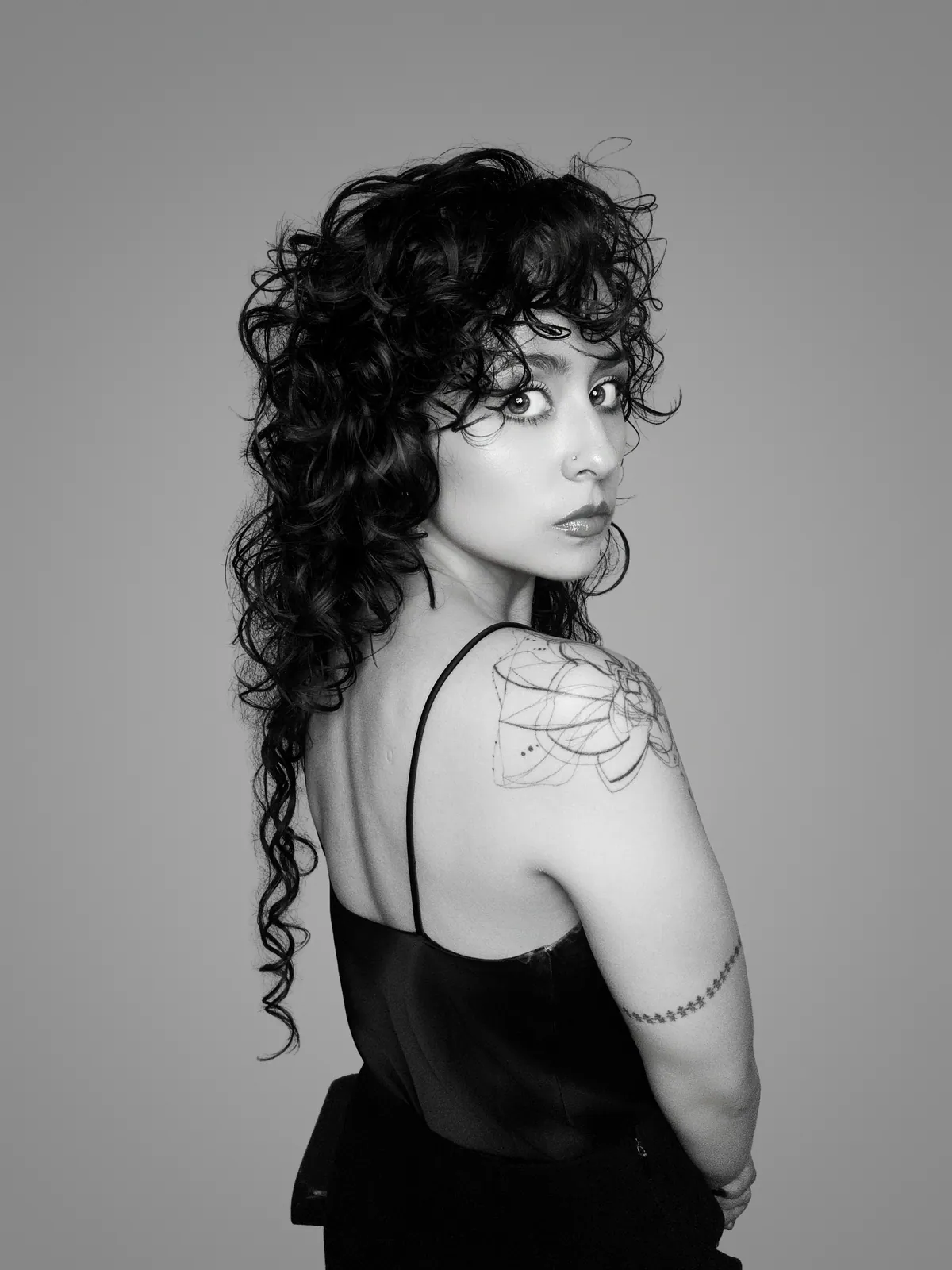 Paula looking toward the camera, showing her shoulder tattoo